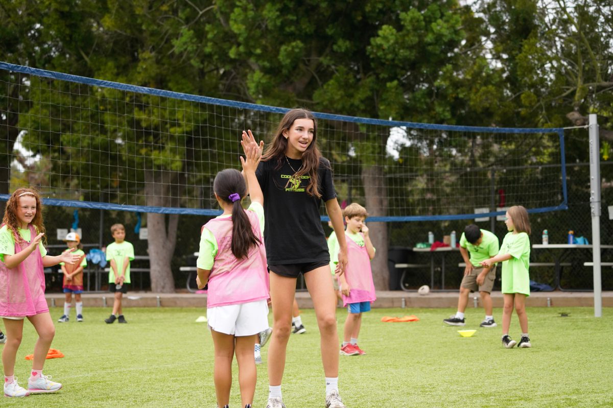 Camp counselor high-fiving a young athlete