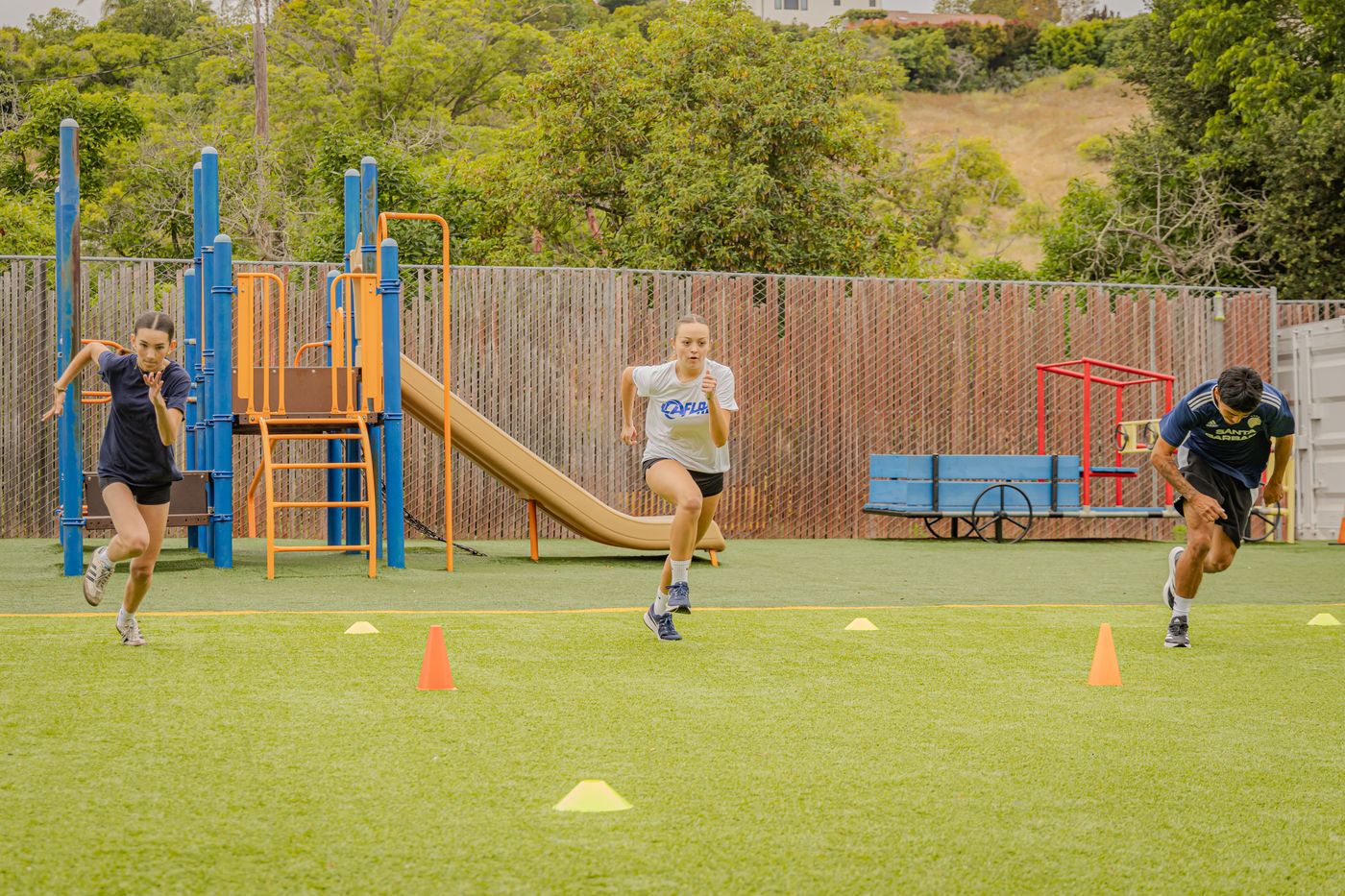 Three young athletes sprinting through cones